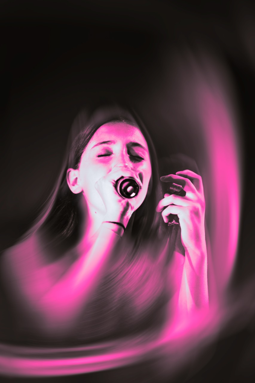 Una cantante si esibisce al microfono tra luci rosa e nere