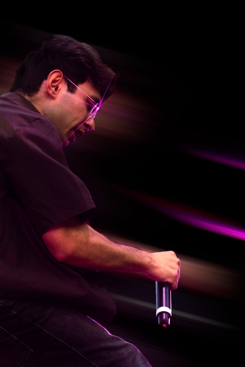 Un artista sul palco con il microfono tra scie di luce viola